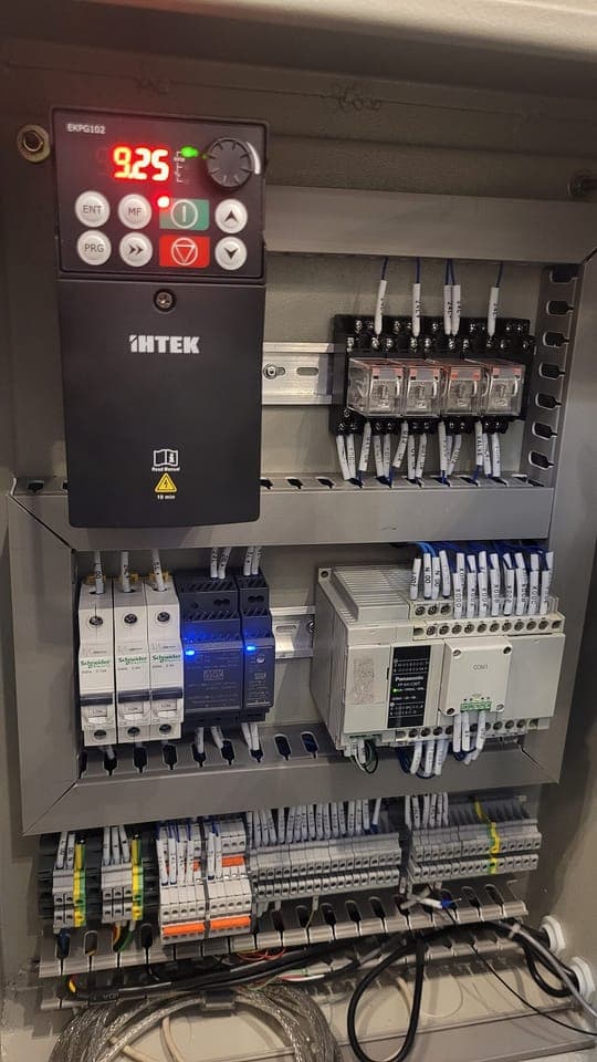 A control panel with a PLC, drive, breakers and relays